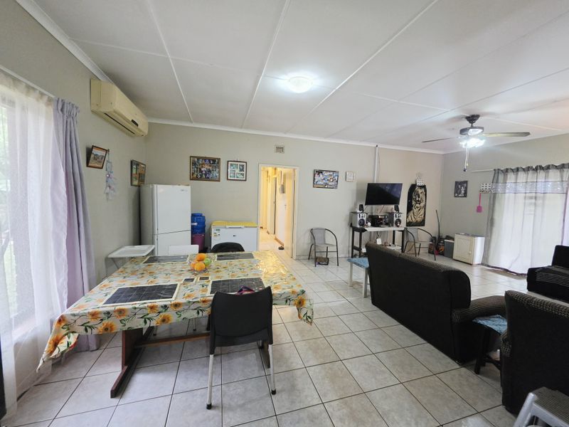 Spacious open-plan living and dining area featuring tiled flooring, a ceiling fan, and a wall-mounted air conditioning unit.