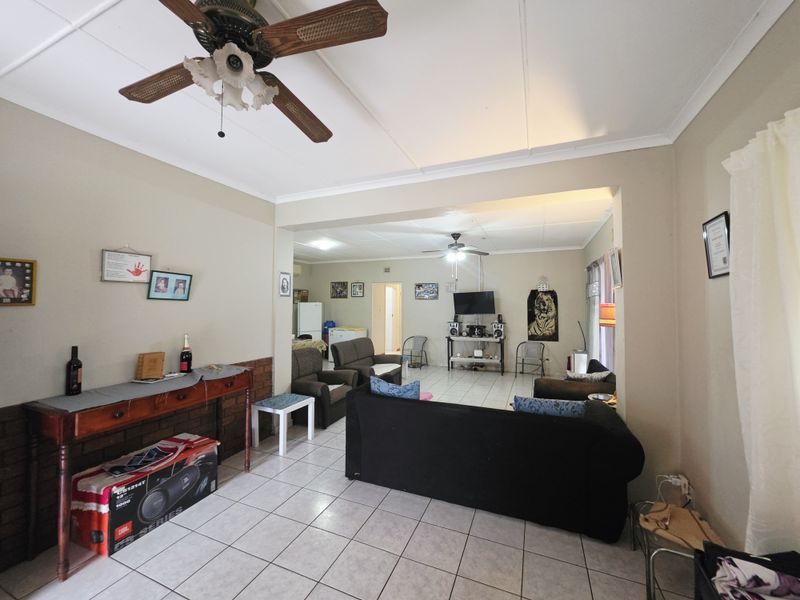 Spacious open-plan living area featuring tiled flooring, ceiling fans, and a neutral color palette, offering a versatile layout for comfortable family living.