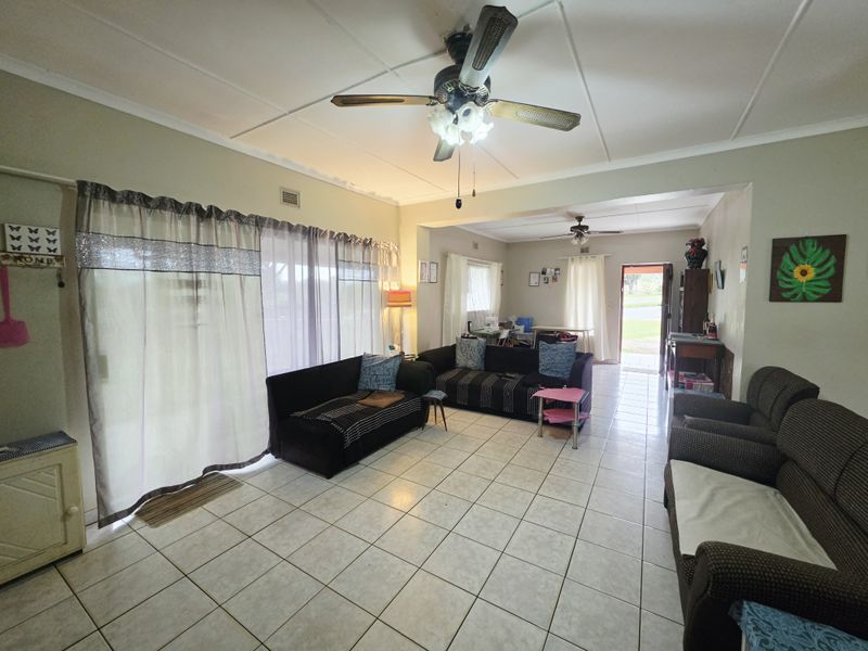 Spacious open-plan living area featuring tiled flooring, ceiling fans, and large sliding glass doors providing natural light and access to the exterior.