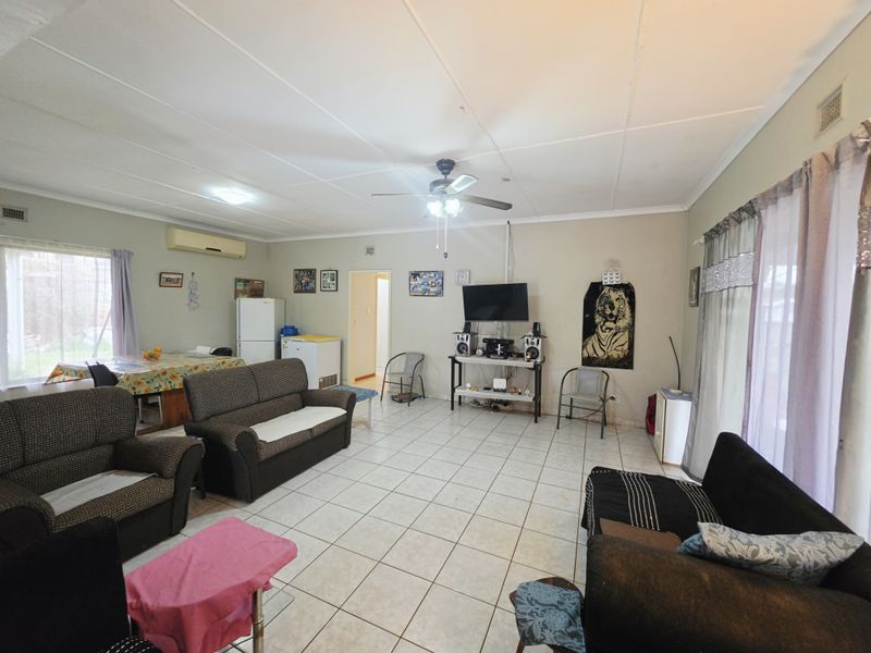 Spacious open-plan living and dining area featuring tiled flooring, a ceiling fan, and split-system air conditioning with access to the exterior.