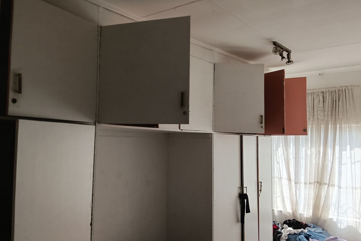 Bedroom featuring extensive built-in cabinetry with overhead storage units and integrated track lighting.