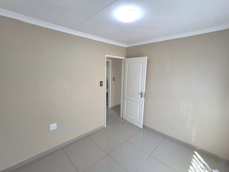 A clean, empty bedroom featuring neutral wall paint, tiled flooring, and a coved ceiling, providing a blank canvas for personalization.