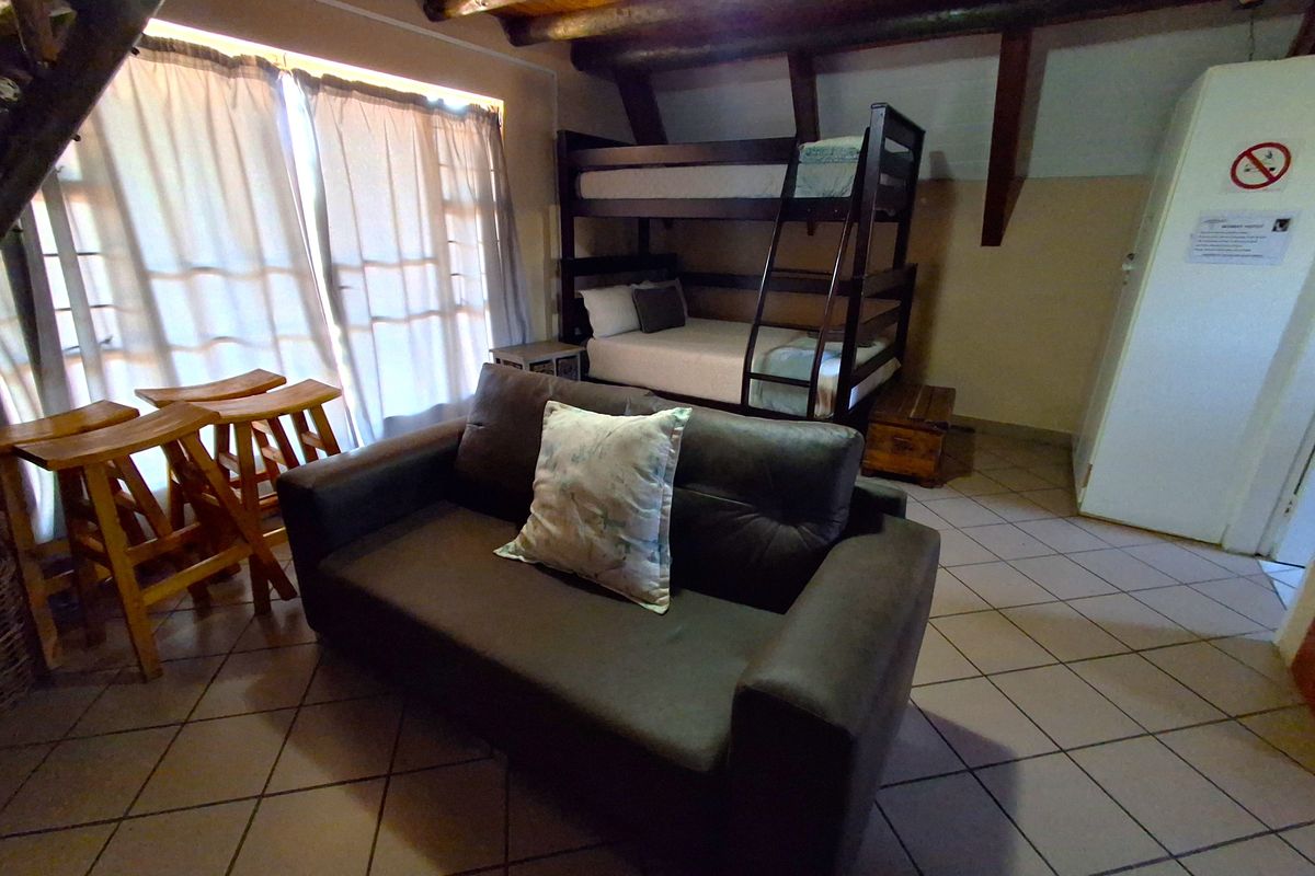 A bedroom featuring exposed timber ceiling beams, tiled flooring, and a sliding glass door providing natural light.