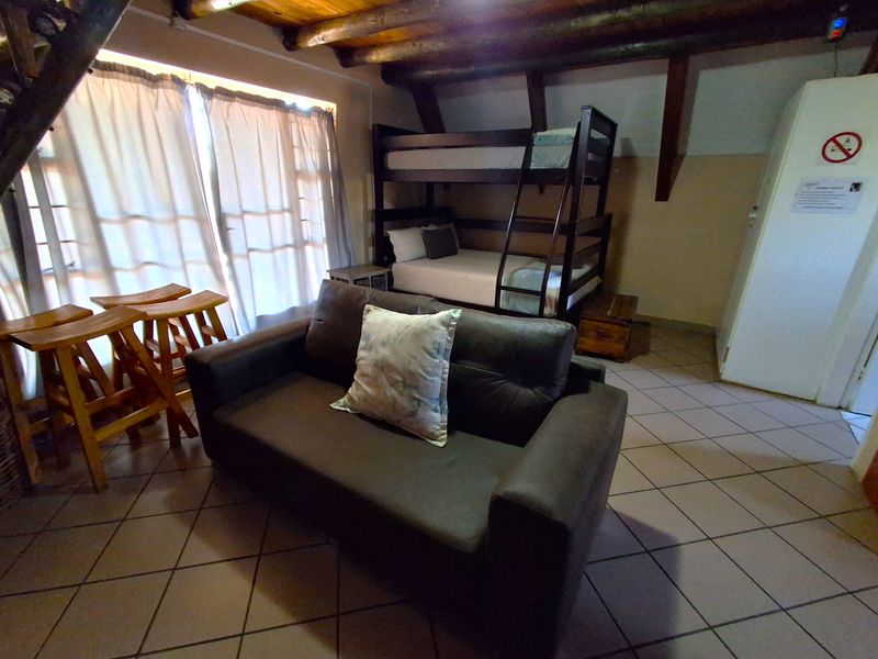 A bedroom featuring exposed timber ceiling beams, tiled flooring, and a sliding glass door providing natural light.