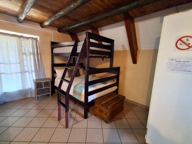 A bedroom featuring exposed timber ceiling beams and tiled flooring, providing a rustic aesthetic.