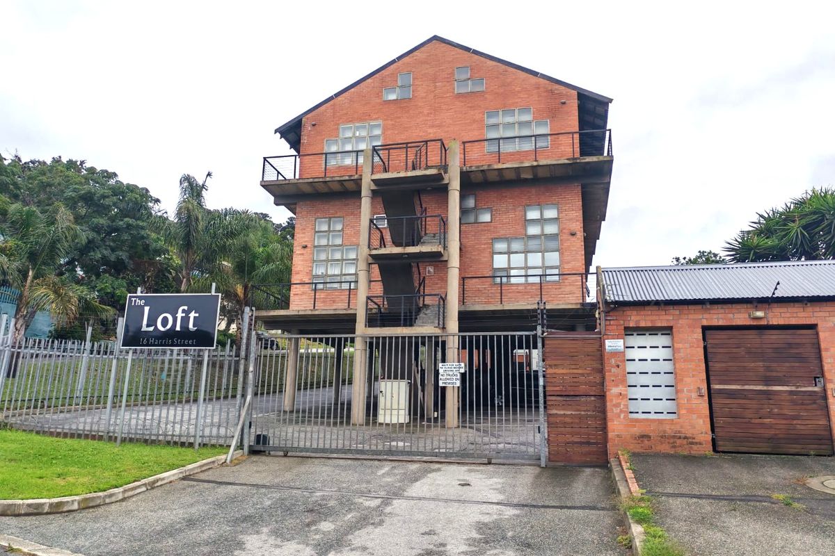 Front view of The Loft apartment building featuring a brick facade, external staircase, balconies, and secure gated access with a private garage.