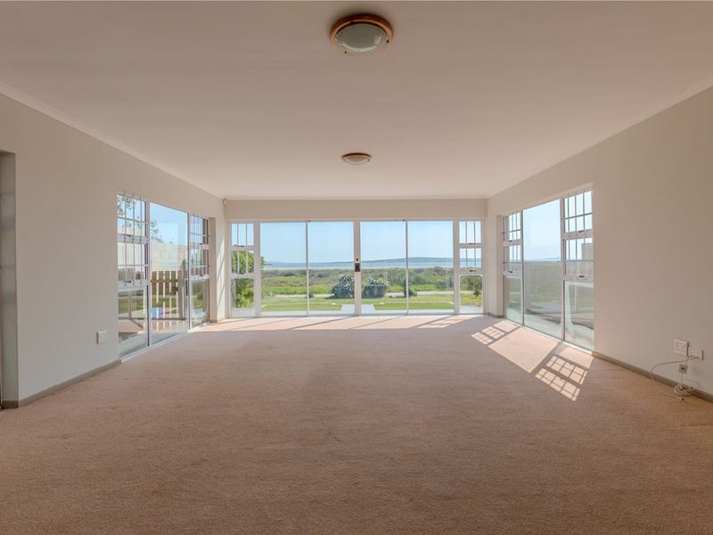 Spacious, light-filled living area featuring expansive sliding glass doors that offer panoramic views and direct access to the outdoors.