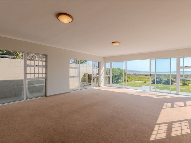 Spacious, sunlit living area featuring expansive sliding glass doors that offer scenic coastal views and direct access to the outdoors.