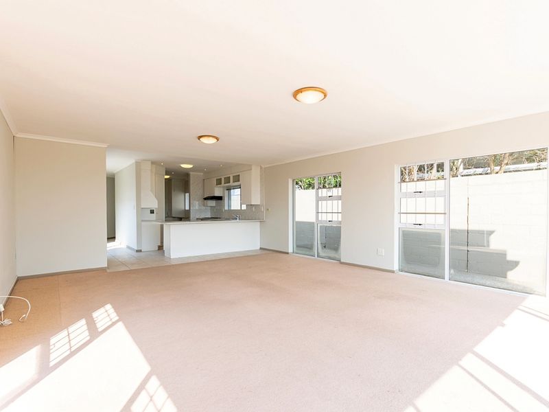 Spacious open-plan living area featuring a functional kitchen with island, neutral carpeting, and large sliding glass doors providing ample natural light.