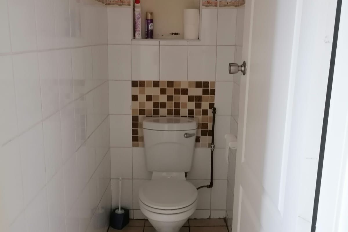 A compact bathroom featuring ceramic wall and floor tiles, a standard toilet, and a recessed wall niche with exposed wiring.