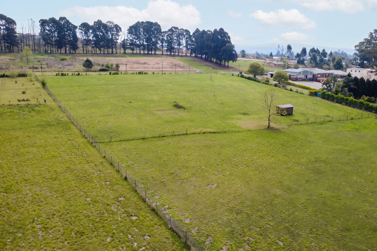 An aerial view of a large, open residential vacant land plot featuring perimeter wire fencing and a small storage shed.