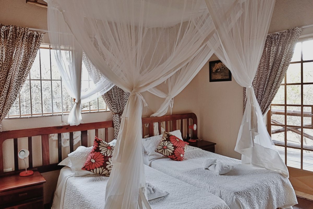 A bedroom featuring a canopy bed setup, timber window and door frames, and security bars on the windows.