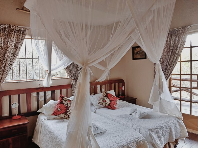 A bedroom featuring a canopy bed setup, timber window and door frames, and security bars on the windows.