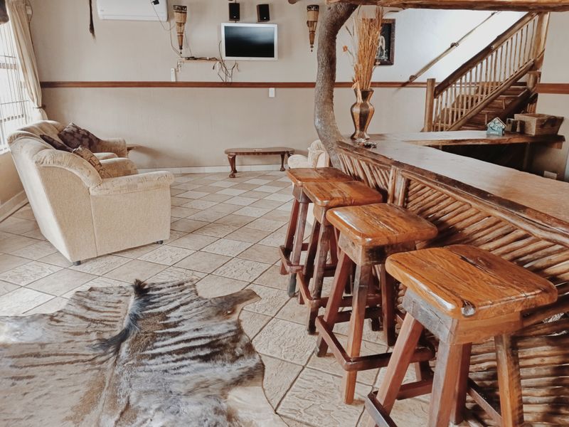 A rustic-style bar area featuring a built-in wooden bar counter, tiled flooring, and an integrated staircase leading to the upper level.