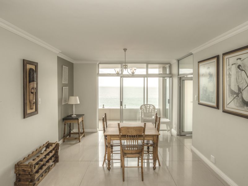 Bright dining area featuring large sliding glass doors that provide natural light and access to an outdoor balcony with ocean views.