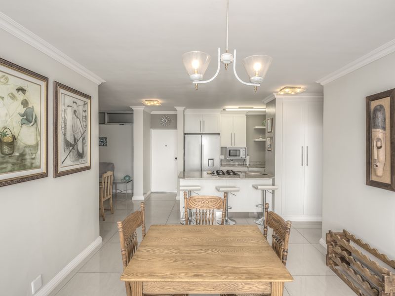 An open-plan living and kitchen area featuring tiled floors, modern cabinetry, stone countertops, and a gas hob, creating a bright and functional space.