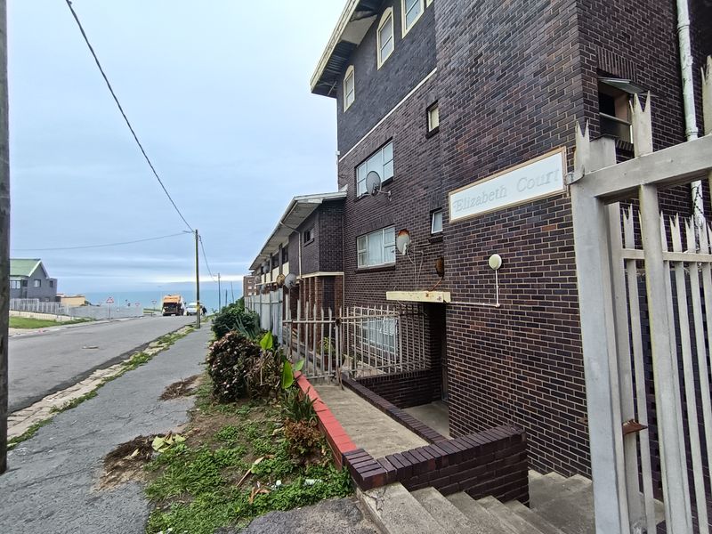 Exterior view of Elizabeth Court apartment building featuring dark brick facade, security fencing, and concrete entrance stairs with street-level access.