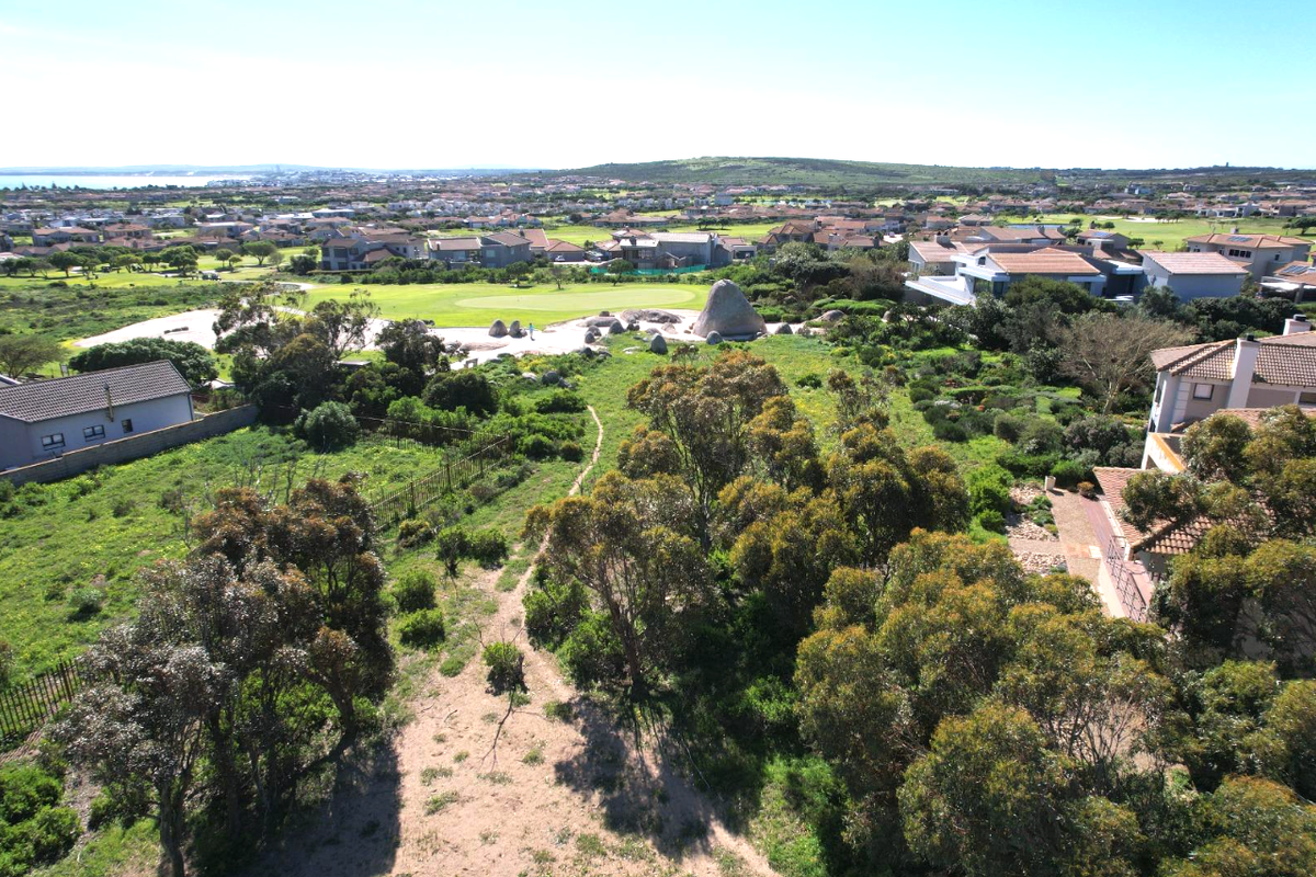 Aerial view of a vacant residential plot featuring natural vegetation, surrounding golf course landscape, and established residential neighborhood context.