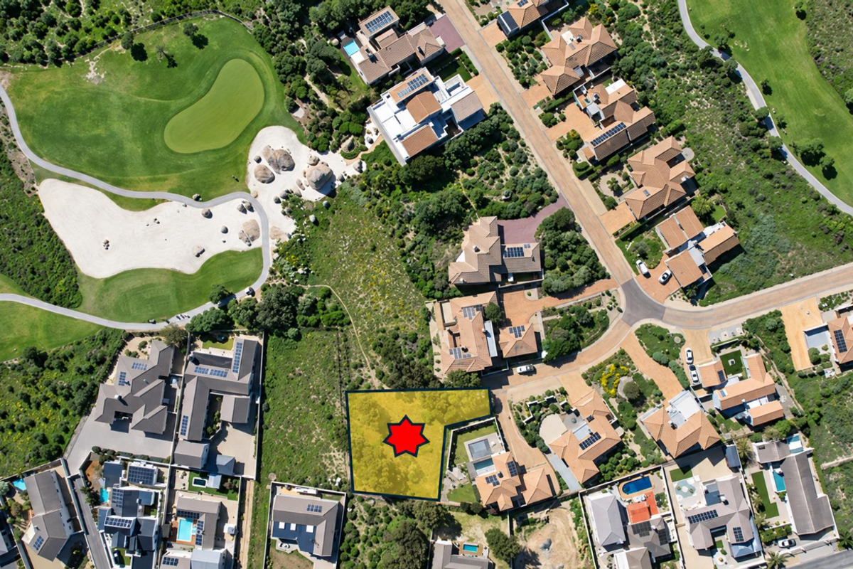 An aerial view of a vacant residential land plot situated within a developed estate, adjacent to a golf course.