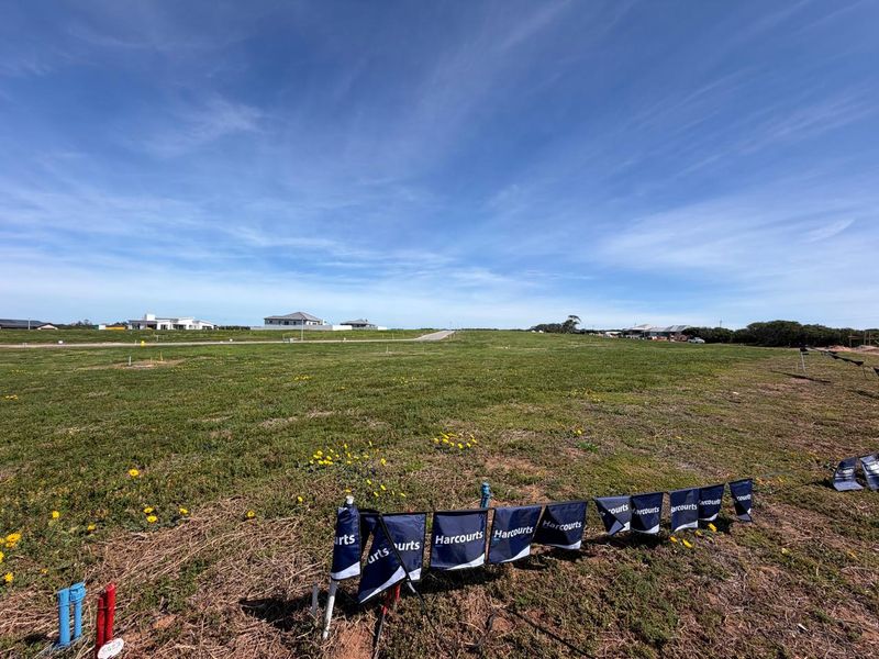 A wide-angle view of a vacant residential plot featuring clear survey markers and utility connection points, ready for development.