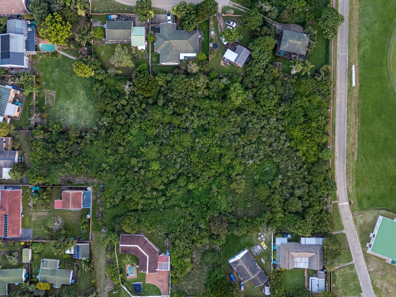 Aerial view of a vacant residential plot densely covered with established vegetation, situated within an established suburban neighborhood.