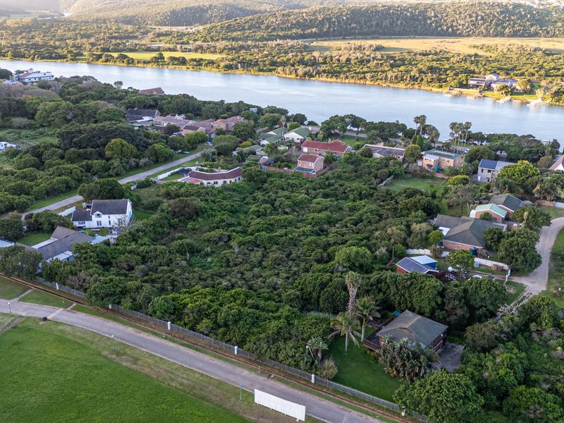 An aerial view of a residential area featuring dense vegetation, nearby river access, and established road infrastructure.