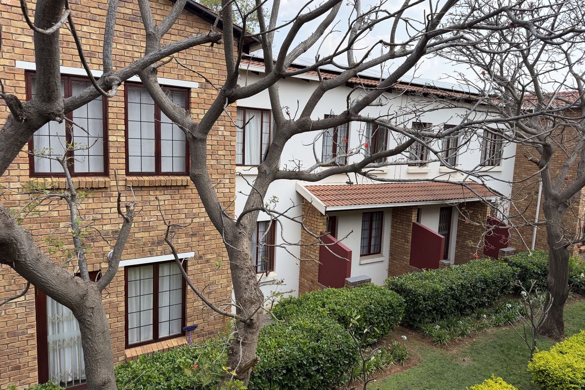 A view of the apartment complex exterior featuring brick and rendered facades, tiled roofing, and well-maintained garden landscaping.