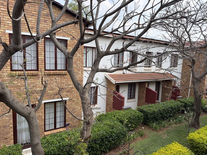 A view of the apartment complex exterior featuring brick and rendered facades, tiled roofing, and well-maintained garden landscaping.