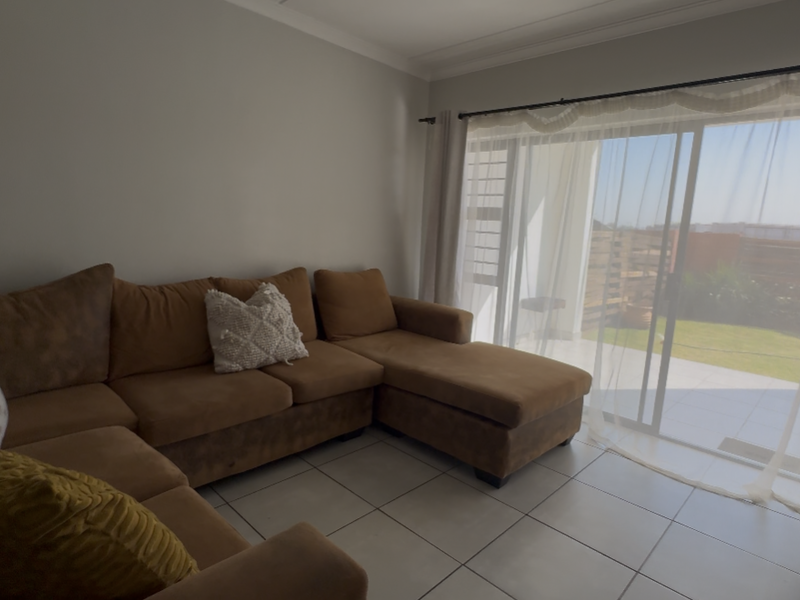 A bright living room featuring large sliding glass doors that provide direct access to an outdoor patio area and garden.