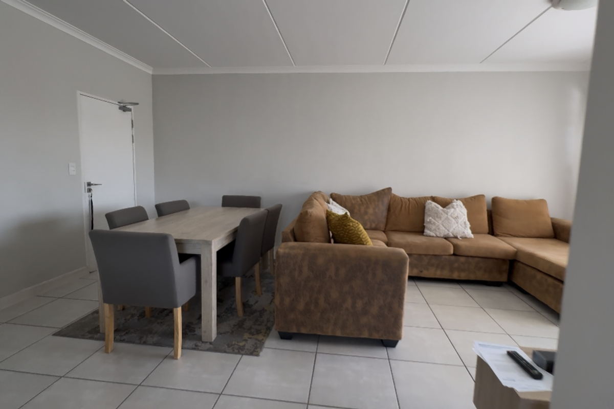 Open-plan living and dining area featuring neutral wall tones and light-colored floor tiles, providing a versatile space for relaxation and meals.