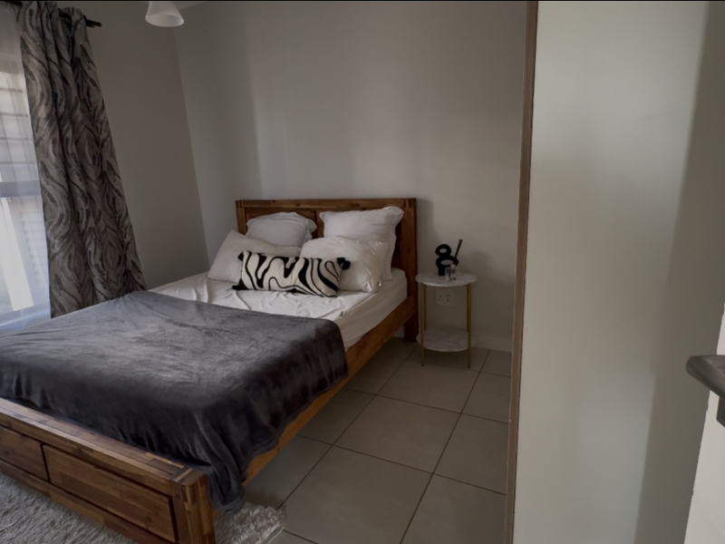 A well-lit bedroom featuring neutral tiled flooring and a built-in cupboard, offering a clean and functional living space.