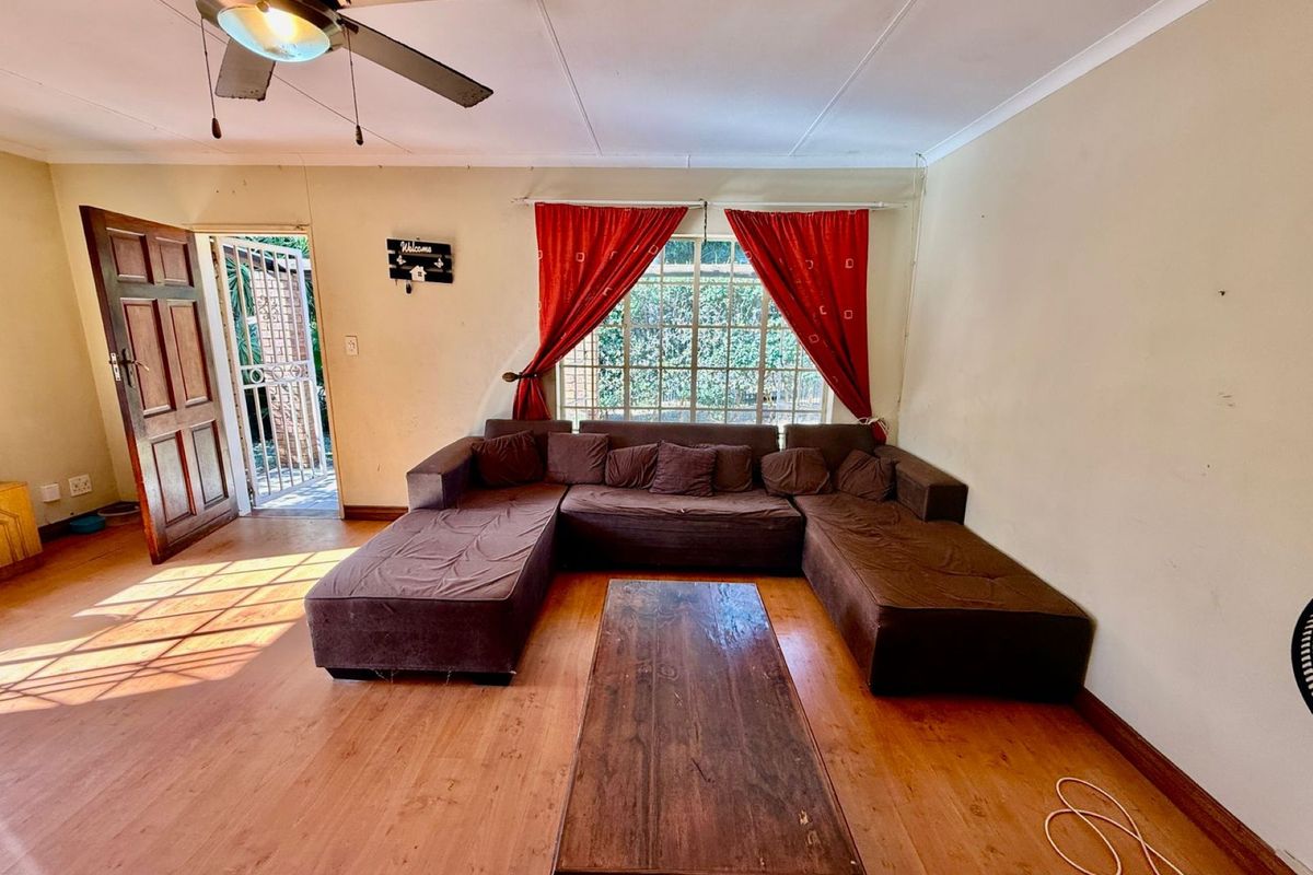 A living room featuring laminate flooring, a ceiling fan, and direct access to an exterior entrance.
