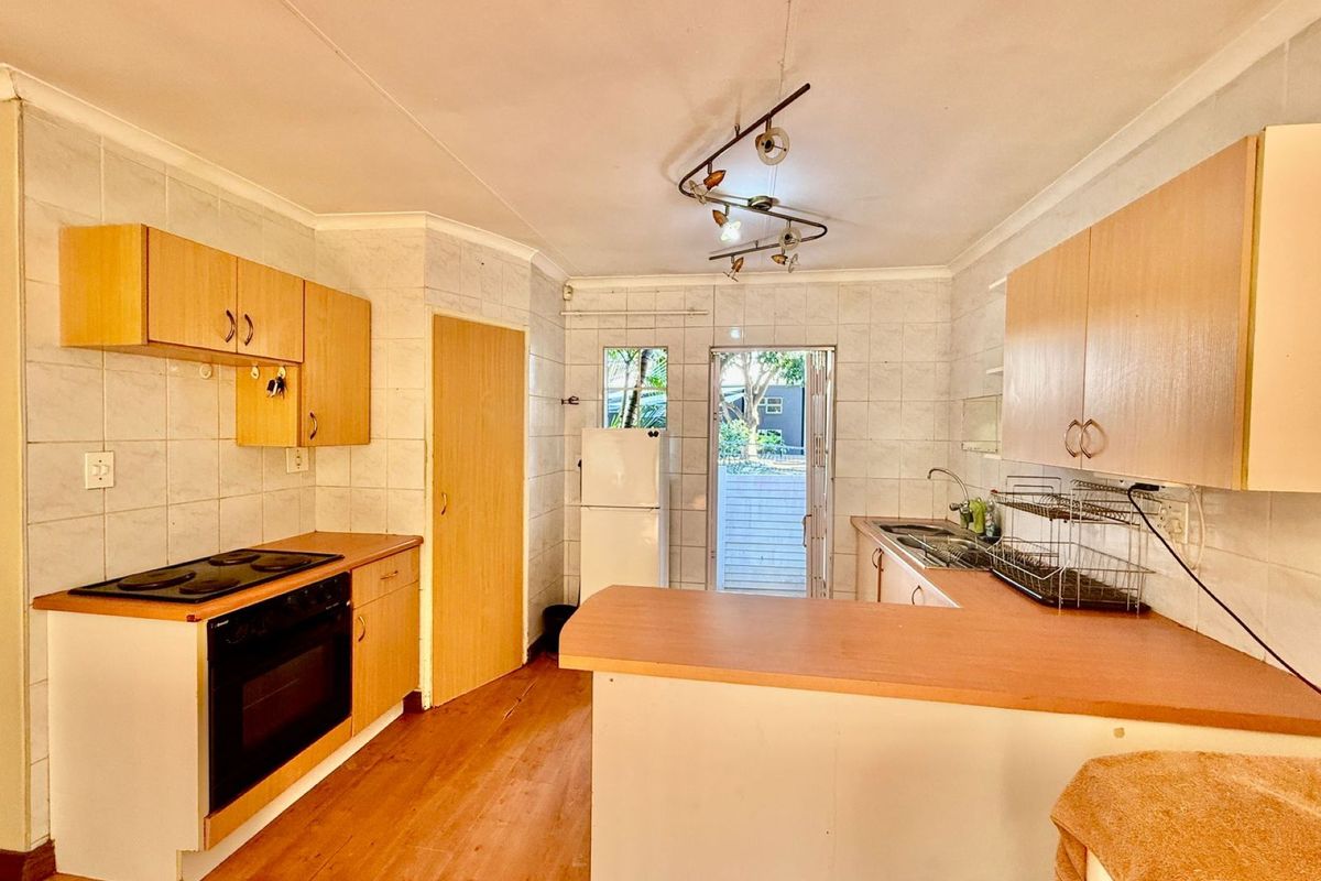 Functional kitchen featuring laminate countertops, built-in oven and hob, ample cabinetry, and direct access to the exterior.