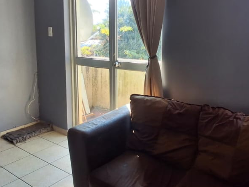 A living room featuring tiled flooring, aluminium window frames, and a sliding glass door providing access to an outdoor area.