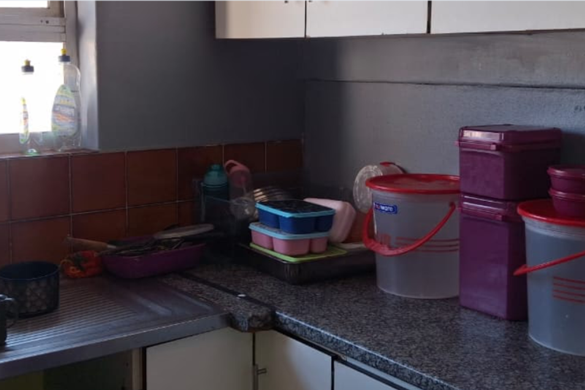 A functional kitchen area featuring a stainless steel sink, tiled splashback, and laminate countertops with built-in cabinetry.