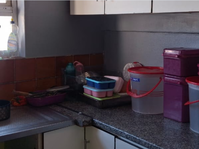 A functional kitchen area featuring a stainless steel sink, tiled splashback, and laminate countertops with built-in cabinetry.