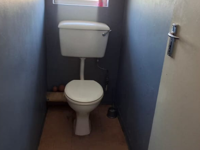A small, functional toilet room featuring dark painted walls and tiled flooring.