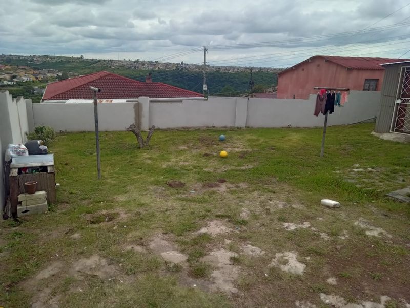 A rear garden area featuring a perimeter wall, patchy lawn, and metal washing lines, offering potential for landscaping and outdoor improvement.