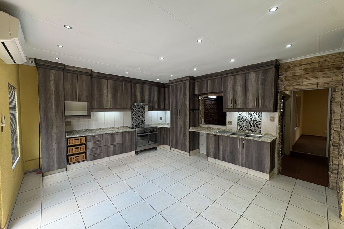 Spacious kitchen featuring dark wood cabinetry, granite countertops, stainless steel appliances, and tiled flooring with recessed lighting.