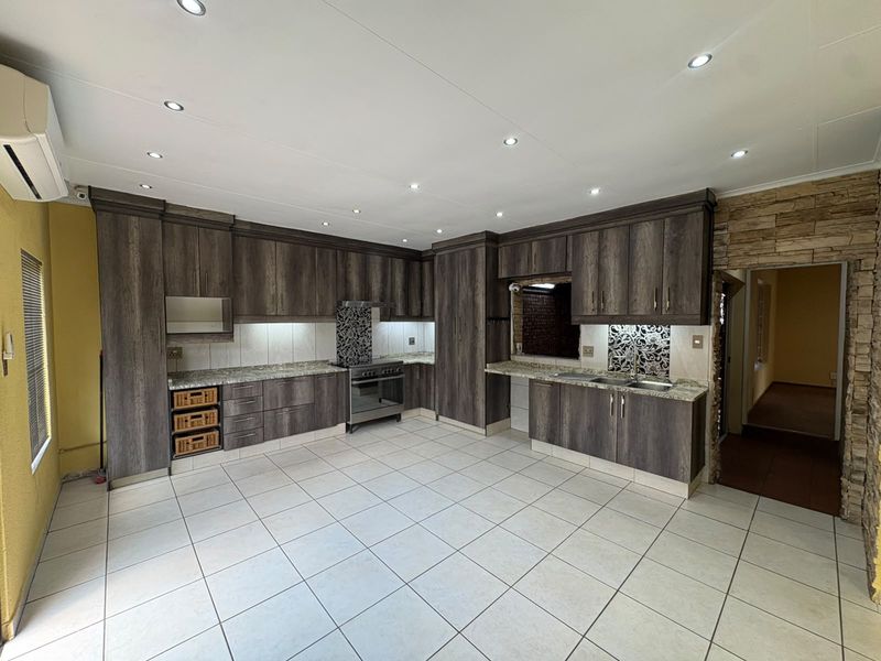Spacious kitchen featuring dark wood cabinetry, granite countertops, stainless steel appliances, and tiled flooring with recessed lighting.