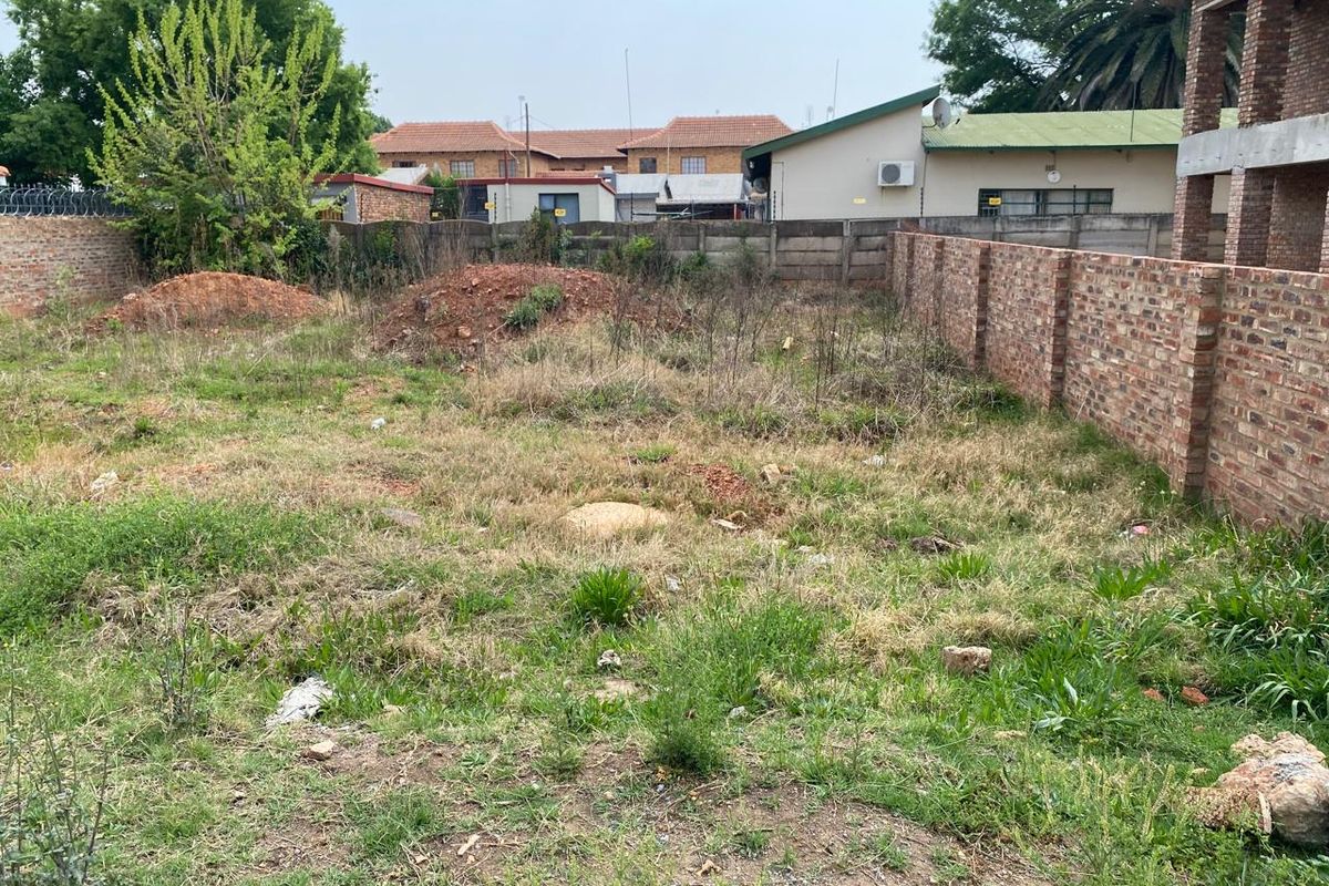 A vacant residential plot featuring established brick boundary walls and perimeter fencing, ready for development.