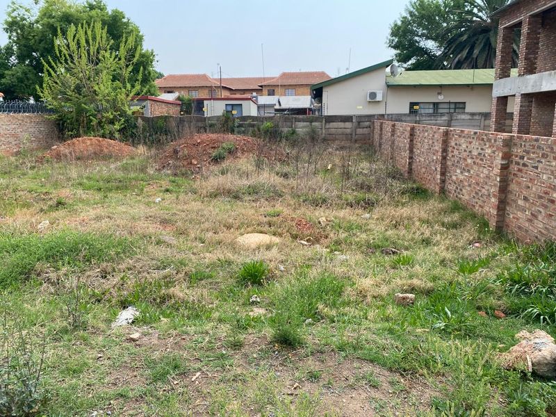 A vacant residential plot featuring established brick boundary walls and perimeter fencing, ready for development.