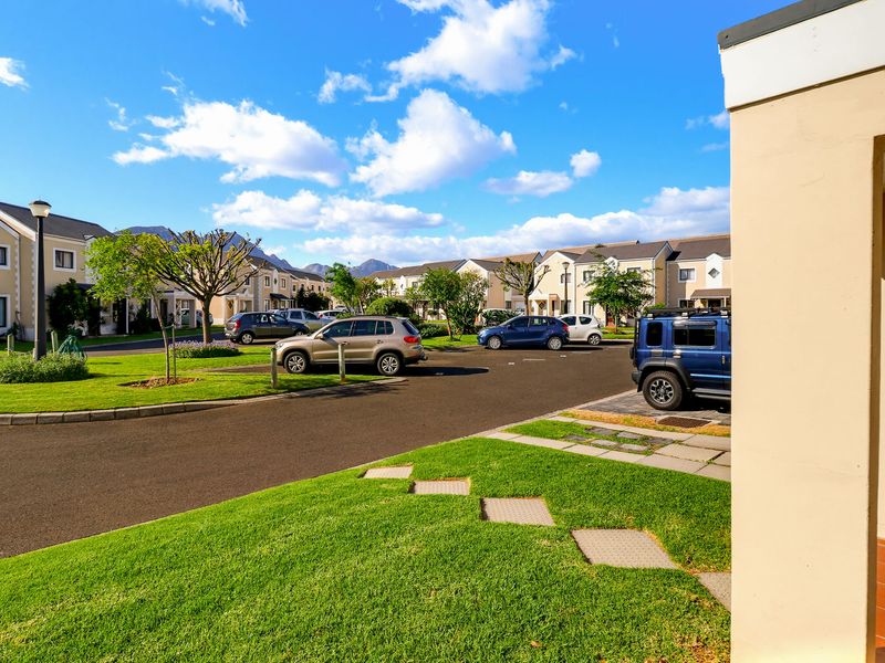 A view of the townhouse complex exterior, featuring well-maintained lawns, paved driveways, and a clear view of the surrounding residential estate.