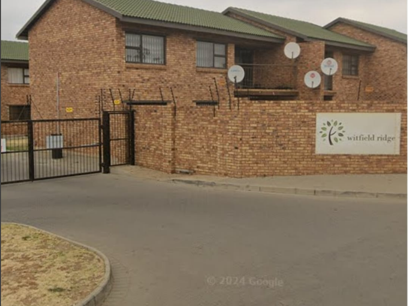 Street view of the Witfield Ridge complex entrance, featuring face-brick construction, secure gated access, and perimeter electric fencing.
