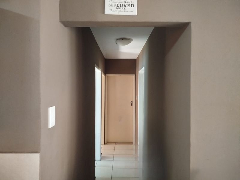 A neutral-toned hallway featuring tiled flooring and access to multiple internal rooms.