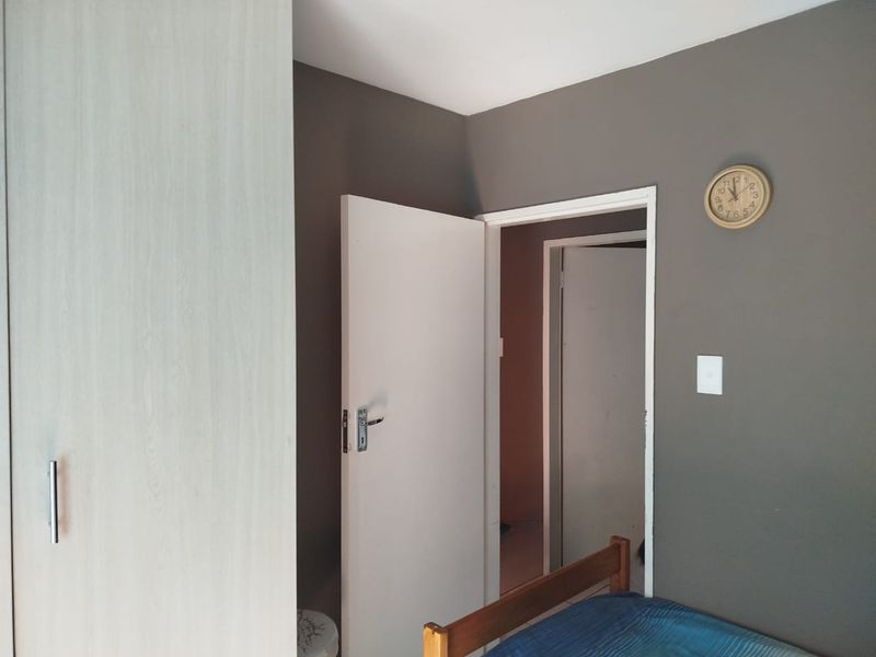A bedroom interior featuring a built-in wardrobe and access to an adjoining room through a standard internal door.