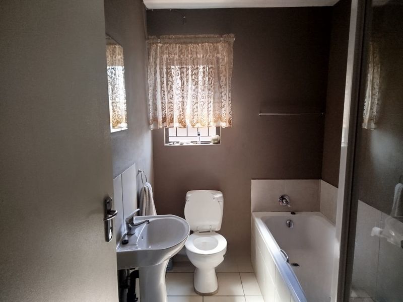 A functional bathroom featuring a pedestal basin, toilet, and bathtub with tiled splashbacks and flooring.