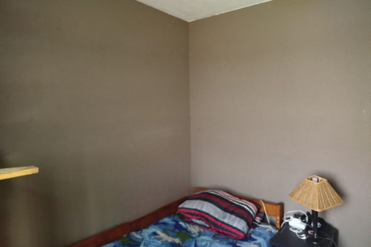 A simple bedroom corner featuring plain painted walls and basic structural finishes.