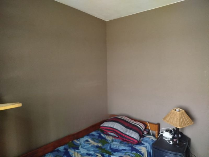 A simple bedroom corner featuring plain painted walls and basic structural finishes.