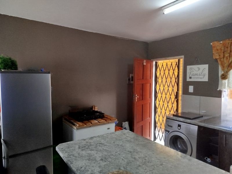 A functional kitchen area featuring a countertop, built-in laundry appliance space, and direct access to an exterior security gate.